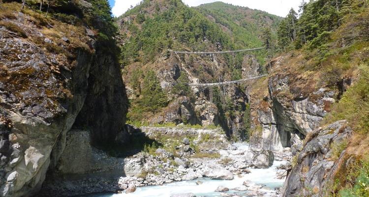 Deux ponts suspendus dans un paysage montagneux avec une rivière en contrebas.