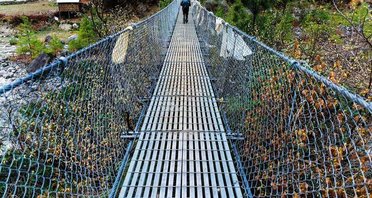 Un pont suspendu étroit au-dessus d'une gorge rocheuse.