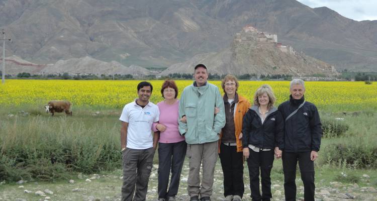 Un grupo de personas paradas en un campo con un monasterio distante.