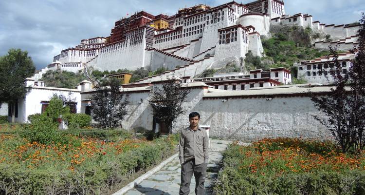 Ein Tourist steht vor dem Potala-Palast, der von Gärten umgeben ist.