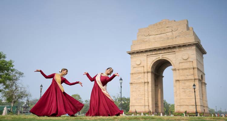 Two dancers posing in front of India Gate
