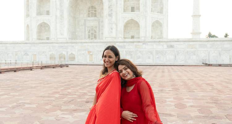 Deux femmes en saris rouges souriantes devant le Taj Mahal
