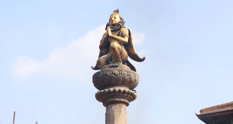 A golden statue of a deity atop a column.