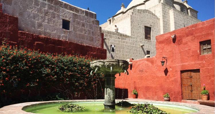Innenhof mit einem Brunnen und lebendigen roten und steinfarbenen Wänden.