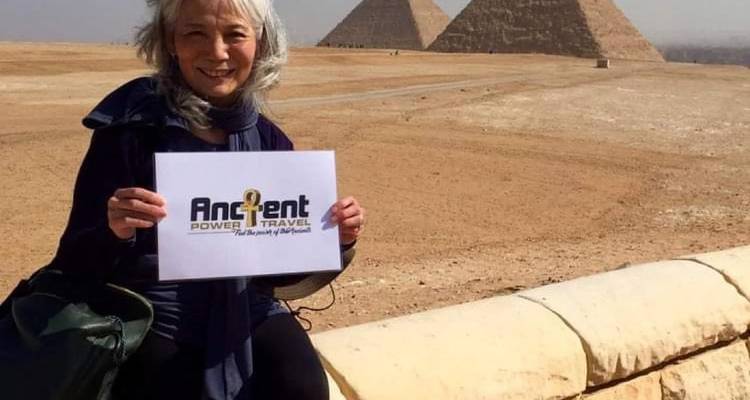 Frau hält ein Schild mit Pyramiden im Hintergrund.