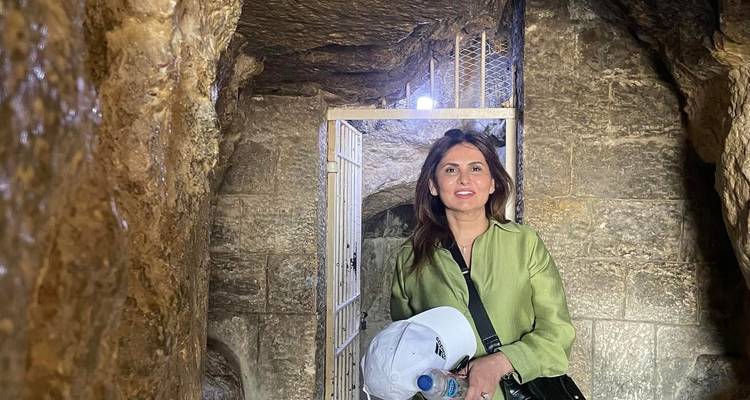 Frau in einer Steinstruktur, die eine Wasserflasche hält.