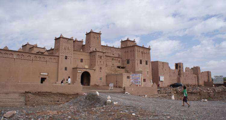 A large traditional Moroccan structure with people walking nearby.