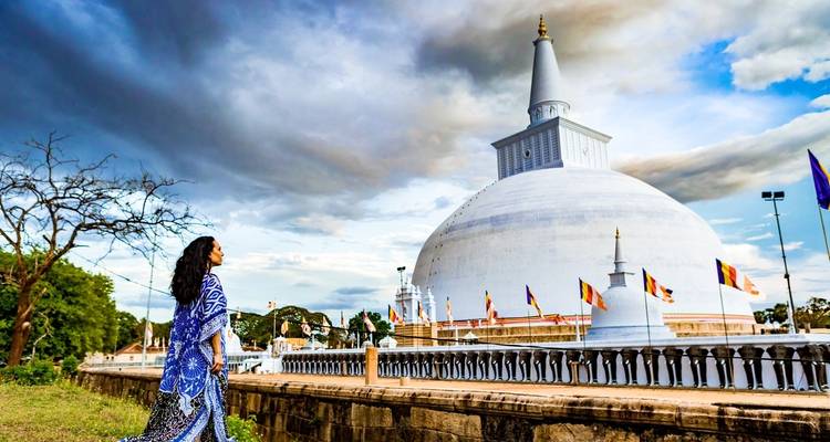 Stupa mit einer Person in traditioneller Kleidung, die ihn betrachtet.
