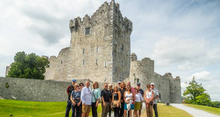 A group of people standing in front of a historic stone castle.
