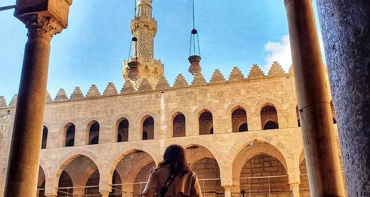 Femme regardant vers le haut dans une belle cour de mosquée historique.