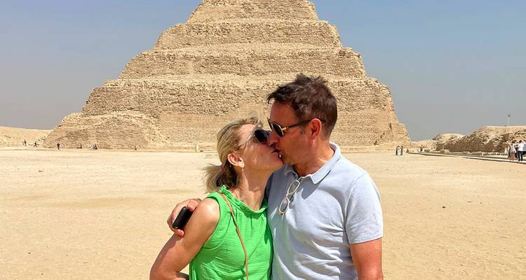 Couple s'embrassant devant une pyramide à degrés.