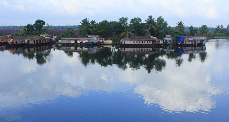 Rangée de péniches habitables sur un plan d'eau réfléchissant.