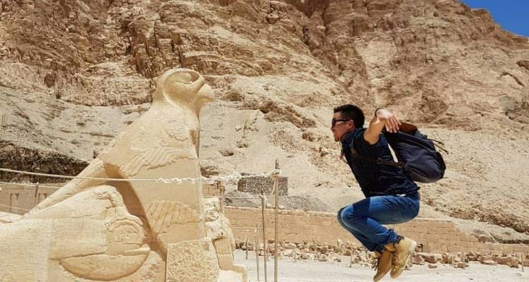 Mann, der neben einer Falkenstatue an einer historischen Stätte springt.