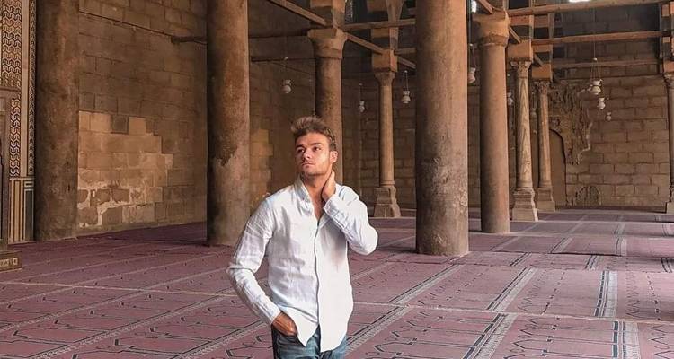 Mann in einem weißen Hemd in einer historischen Moschee.