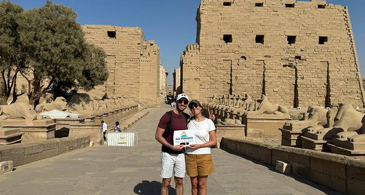 Couple standing in front of an ancient temple with statues.