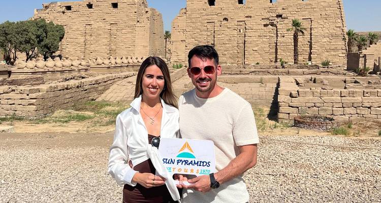 Couple avec un panneau devant une structure de temple ancien.