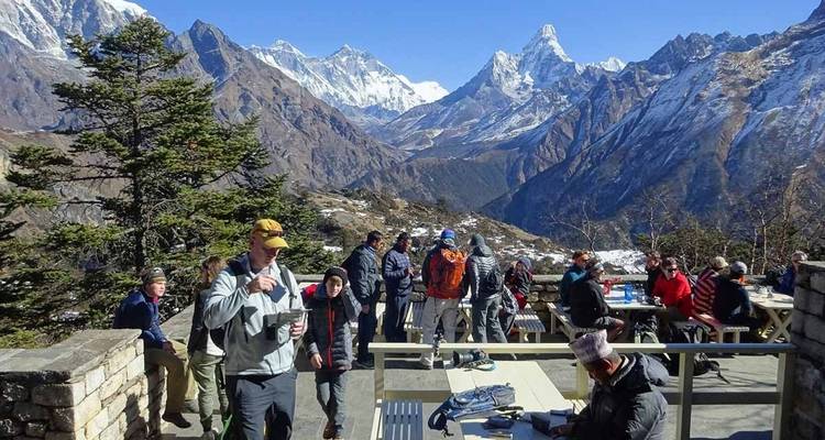 Group of people with snowy mountains and a blue sky as backdrop.