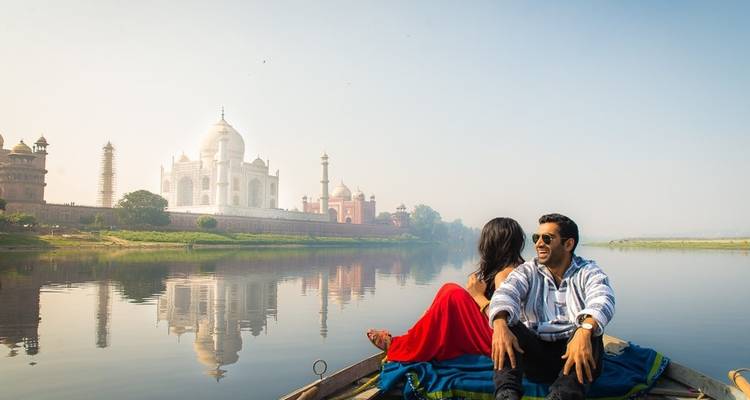 Couple profitant d'une promenade en bateau sur une rivière avec le Taj Mahal en arrière-plan.