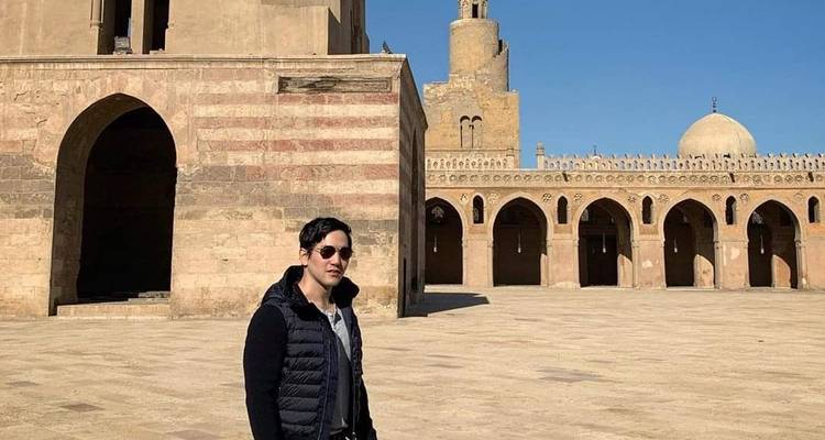A man standing in front of a historic mosque courtyard.