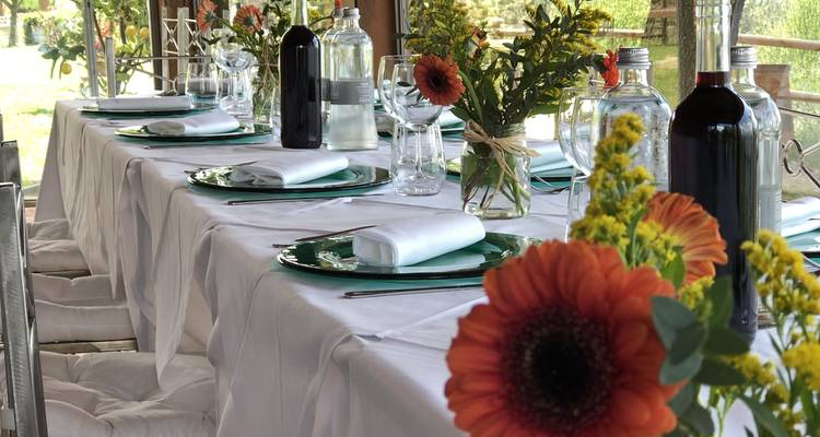 Tischgedeck mit Blumen und Weinflaschen in einem Außenbereich zum Speisen.