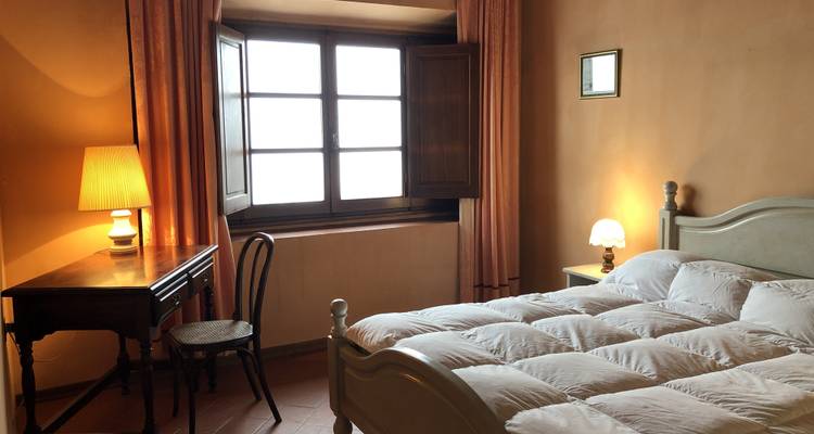 Gemütliches Schlafzimmer mit einem Fenster und einem Holzschreibtisch.