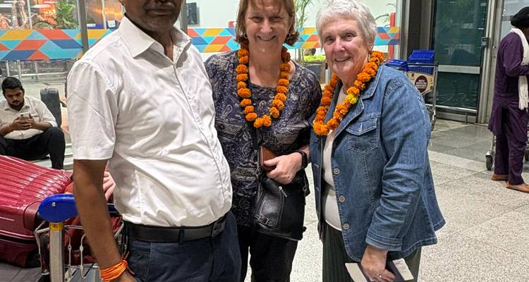 Tres personas sonriendo a la cámara con guirnaldas.
