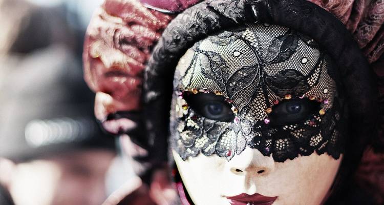 Gros plan d'un masque de carnaval vénitien orné avec de la dentelle noire et des bijoux étincelants.
