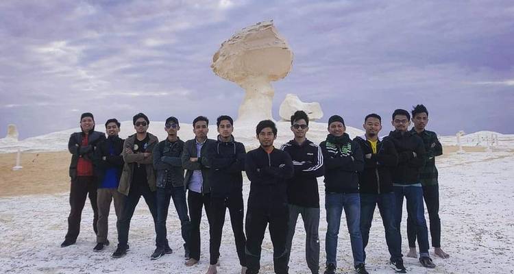 Une photo de groupe de personnes debout devant une grande formation rocheuse du désert.