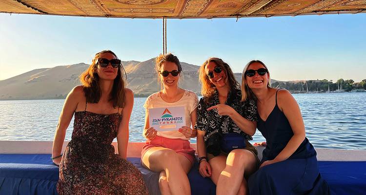 Group of women smiling on a boat with a mountain backdrop.