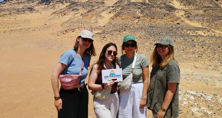 Four women holding a tour sign in a desert area.
