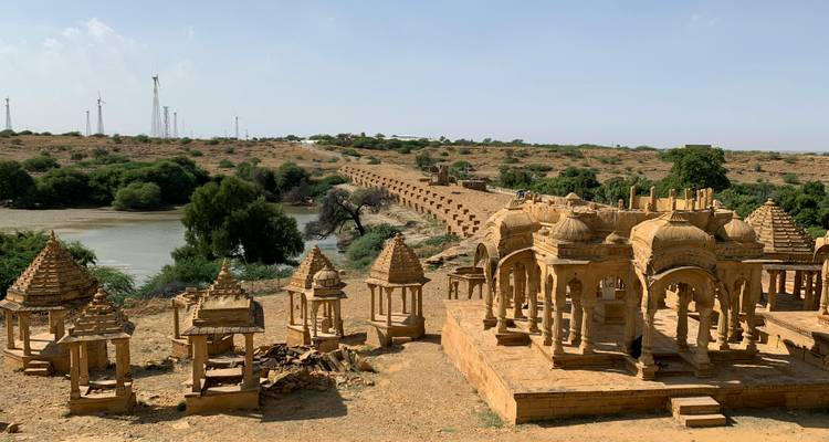 Duplicate landscape of Bada Bagh cenotaphs with desert plain and wind turbines on horizon.