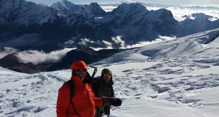 Twee klimmers op een besneeuwde bergkam met verre toppen.