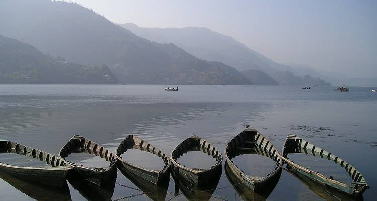 Rangée de canoës sur un lac calme entouré de collines.