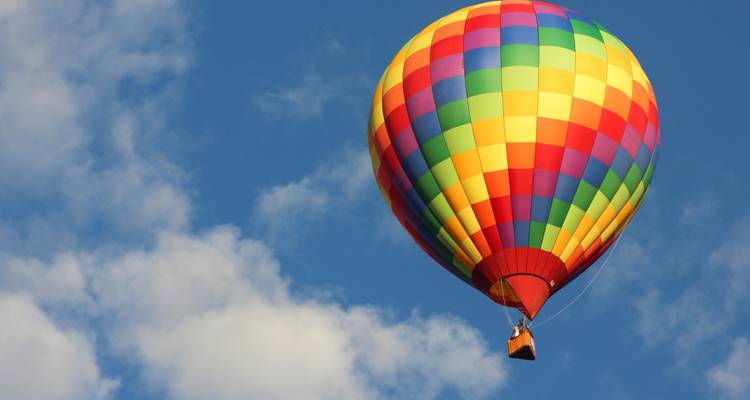 Nahaufnahme eines bunten Heißluftballons vor einem blauen Himmel.