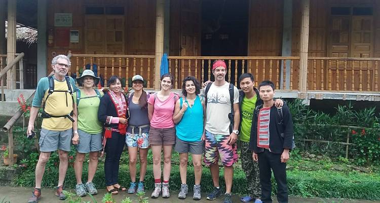 A group of people posing for a photo in front of a wooden house.