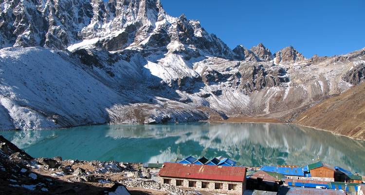 Turquoise lake surrounded by snowy peaks and lodges.