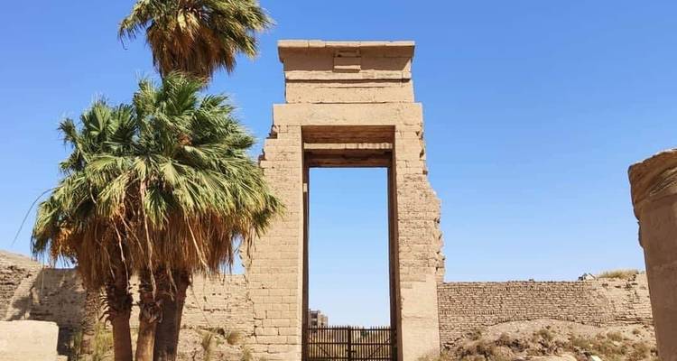 Ein historisches Tor mit Palmen an einem klaren Tag.