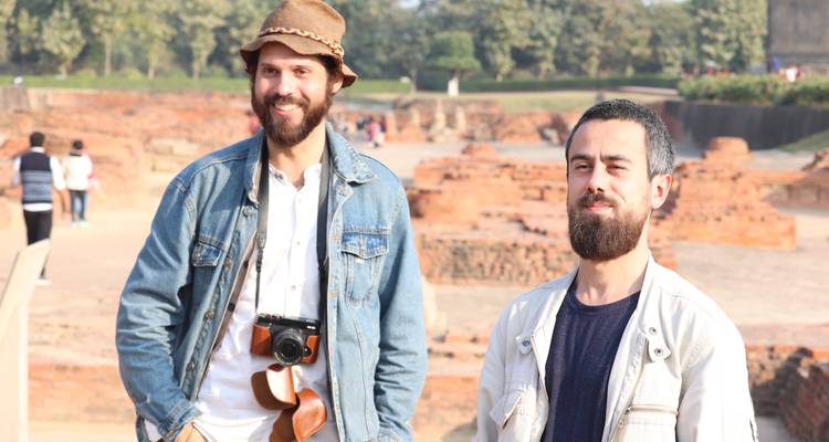 Deux voyageurs masculins sourirent parmi les ruines de briques anciennes et la verdure environnante.