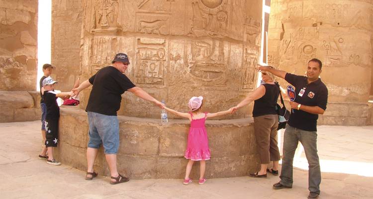 Menschen, die sich an den Händen halten um eine antike Säule mit Hieroglyphen.