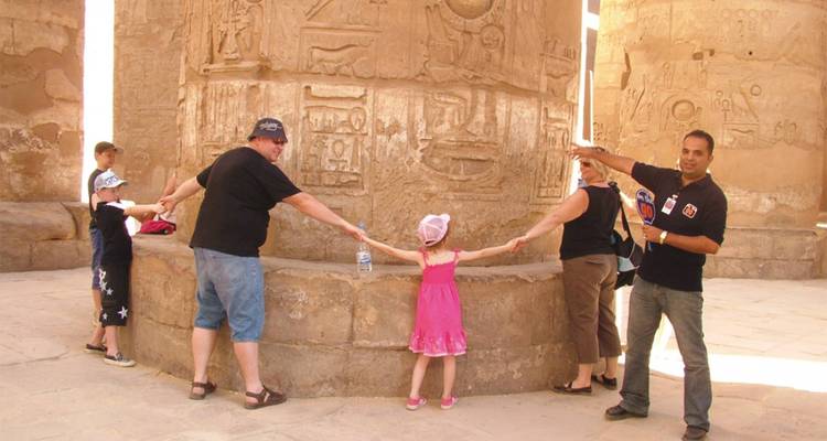 Grupo familiar posando alrededor de una columna antigua con grabados.