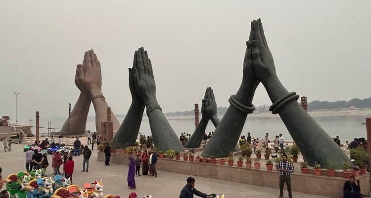 Massive bronzene betende Handskulpturen entlang einer von Besuchern überfüllten Uferpromenade