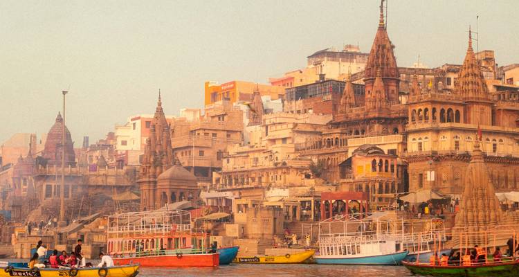 Les ghats colorés et les temples de Varanasi bordent le Gange avec des bateaux remplis de personnes.