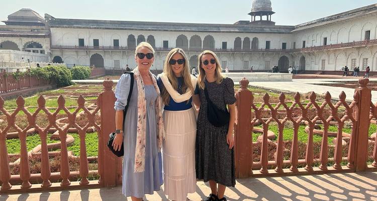 Trois femmes posent dans la cour d'un palais moghol historique avec des balustrades à treillis.
