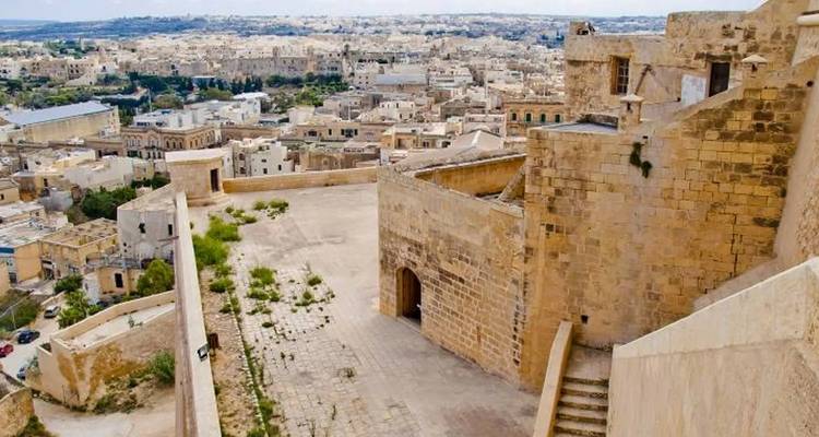 Ruinas de una estructura antigua con vista a una ciudad.