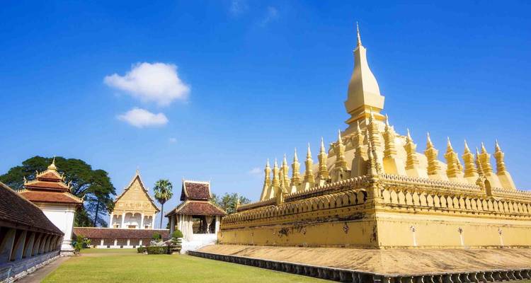 Golden stupa with surrounding temples in a clear sky.
