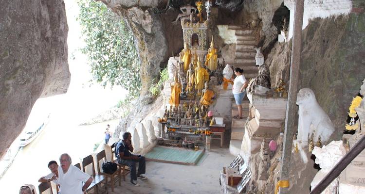 A cave with Buddhist statues and visitors inside.