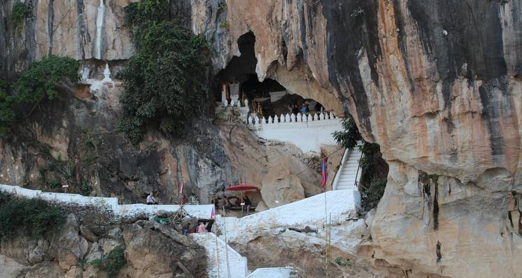 A cave entrance with steps leading up, people exploring.