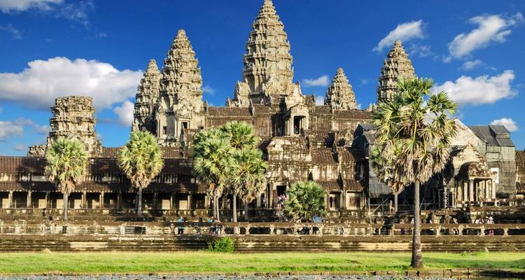 Angkor Wat temple with palm trees and a clear blue sky.