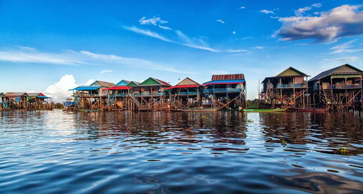 Colorful stilt houses along the water under a blue sky.