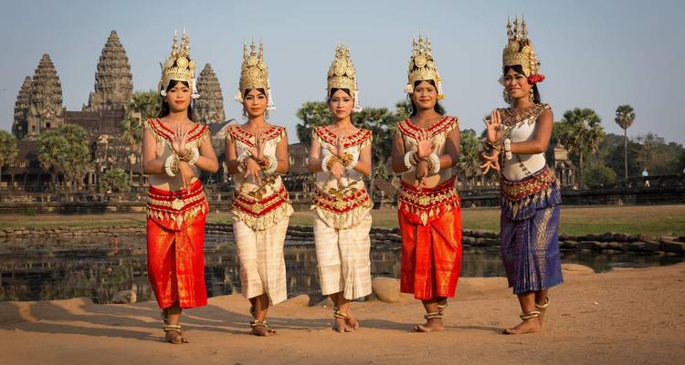 Traditional dancers posing with Angkor Wat temple in the background.